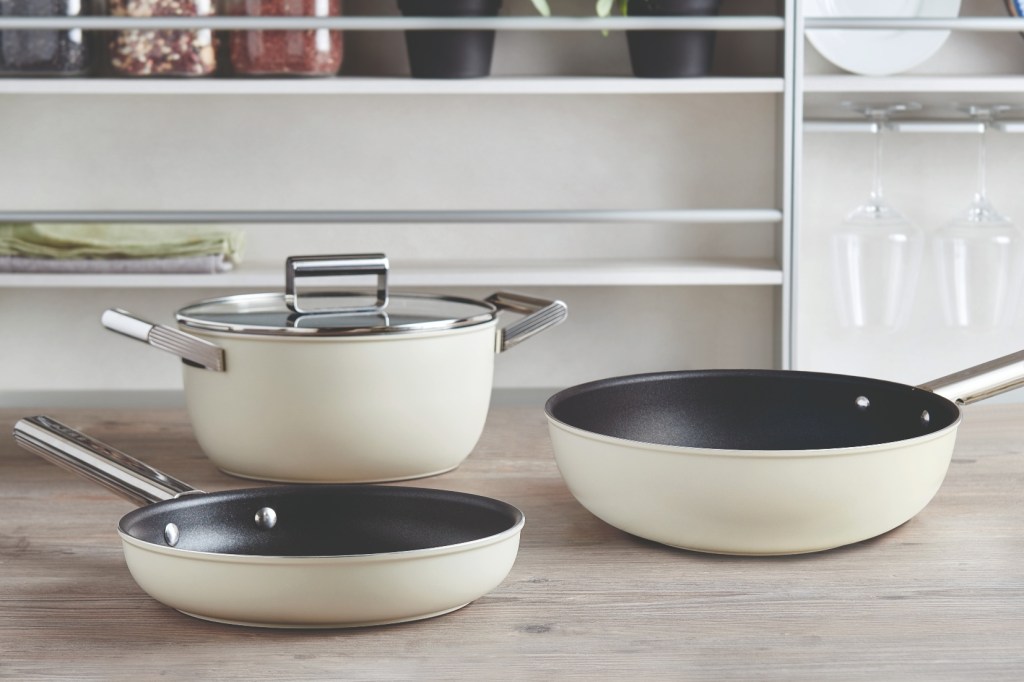 The new Smeg cookware range comprising casserole dish, frying pan and wok in a stylish cream finish