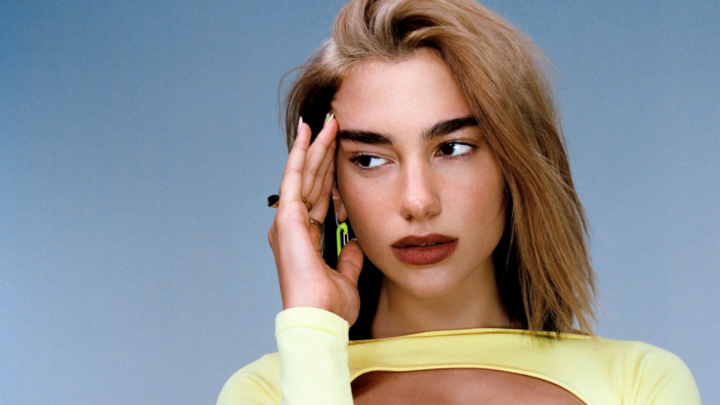 Singer Dua Lipa poses in a yellow dress for a promotional image