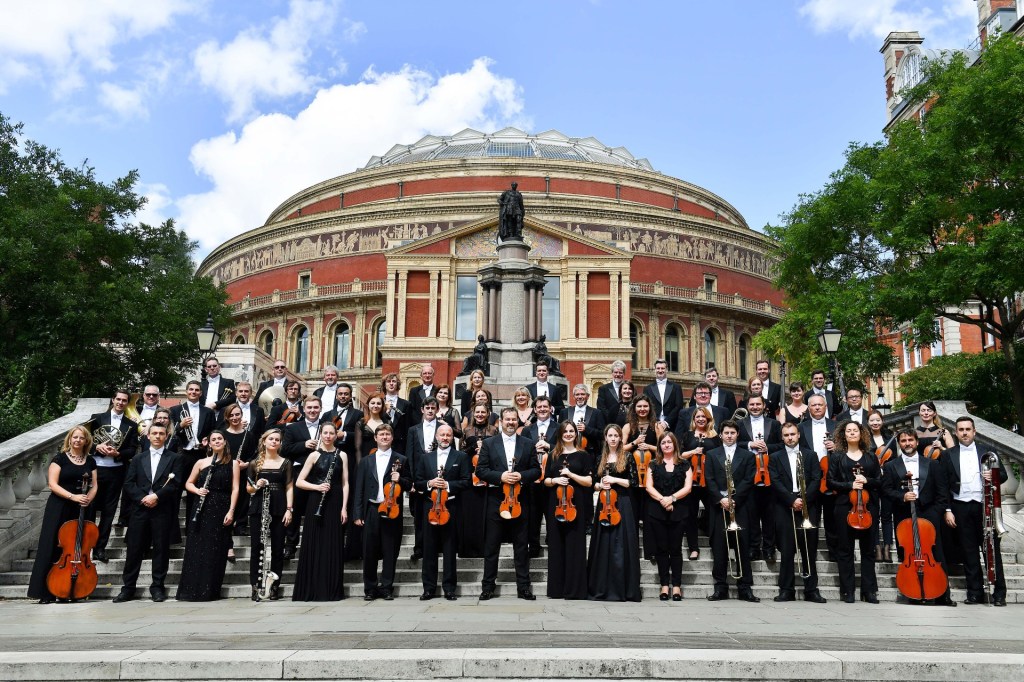 The Royal Philharmonic Orchestra stand on the steps outside the Royal Albert Hall