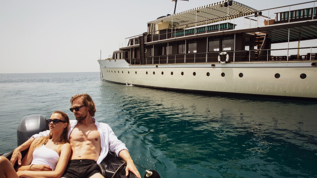 Maid Marion 2 yacht in the background as two bathers enjoy the sun