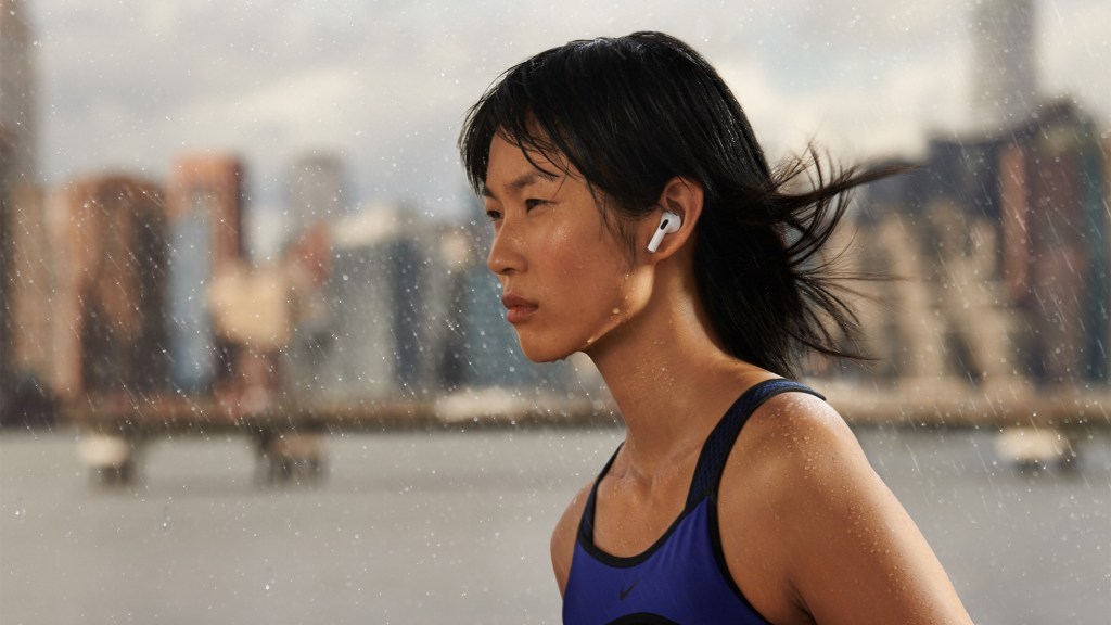 A runner wearing Apple AirPods 3rd Gen jogs through the rain