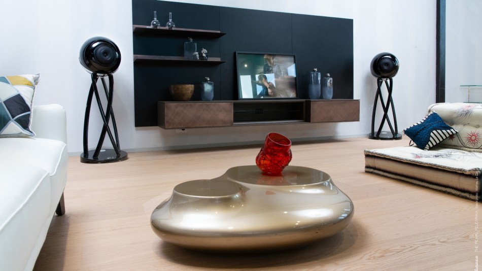 A pair of Cabasse Pearl Pelegrina speakers positioned either side of a small TV in a designer living room