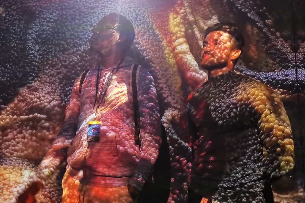 Two viewers covered in projected art at LUX New Wave of Contemporary Art