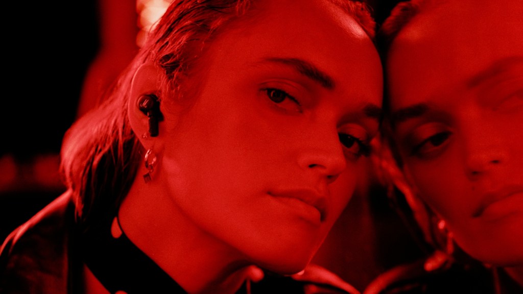 Marshall Motif ANC earbuds worn by a model bathed in red light light