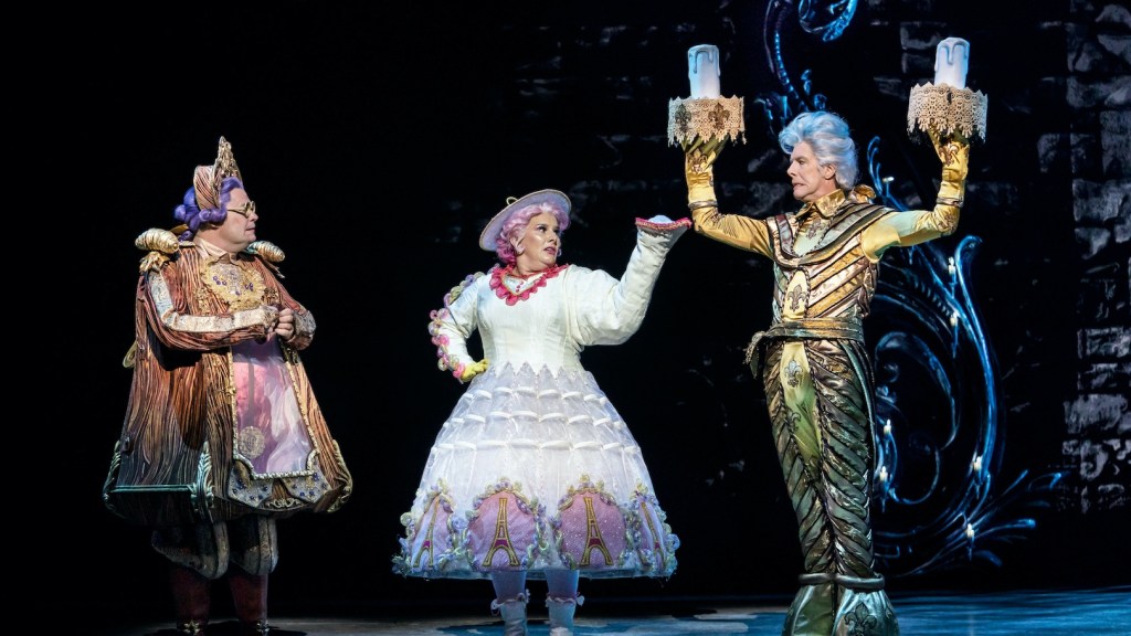 Cogsworth (Nigel Richards), Mrs Potts (Sam Bailey) and Lumiere (Gavin Lee) on stage in Beauty and the Beast