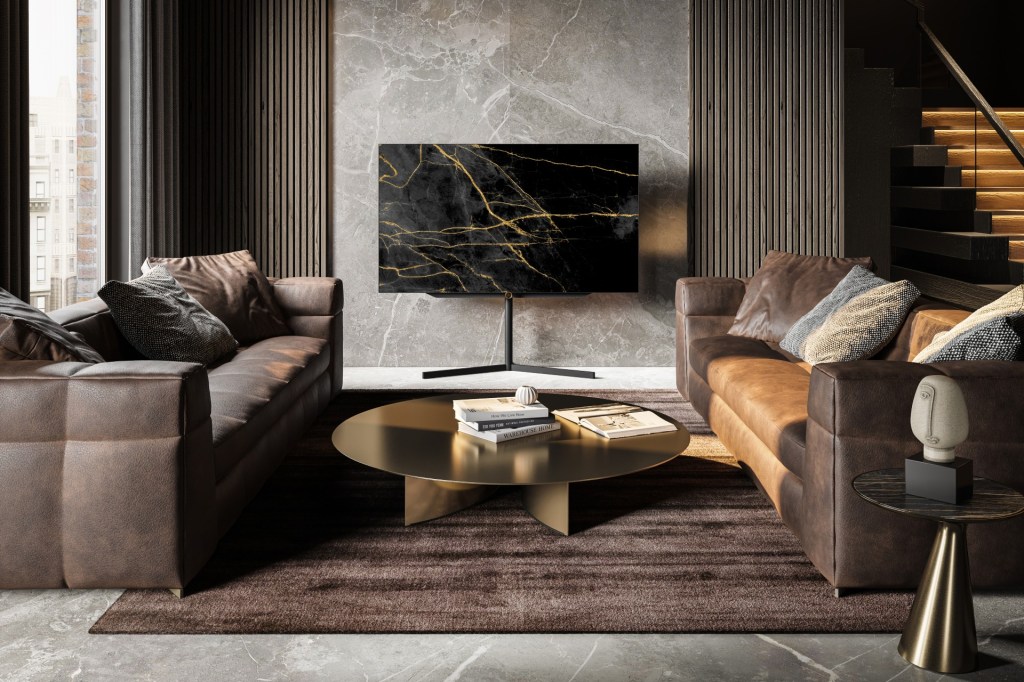 The Loewe bild s.77 TV on a stand between to sofas