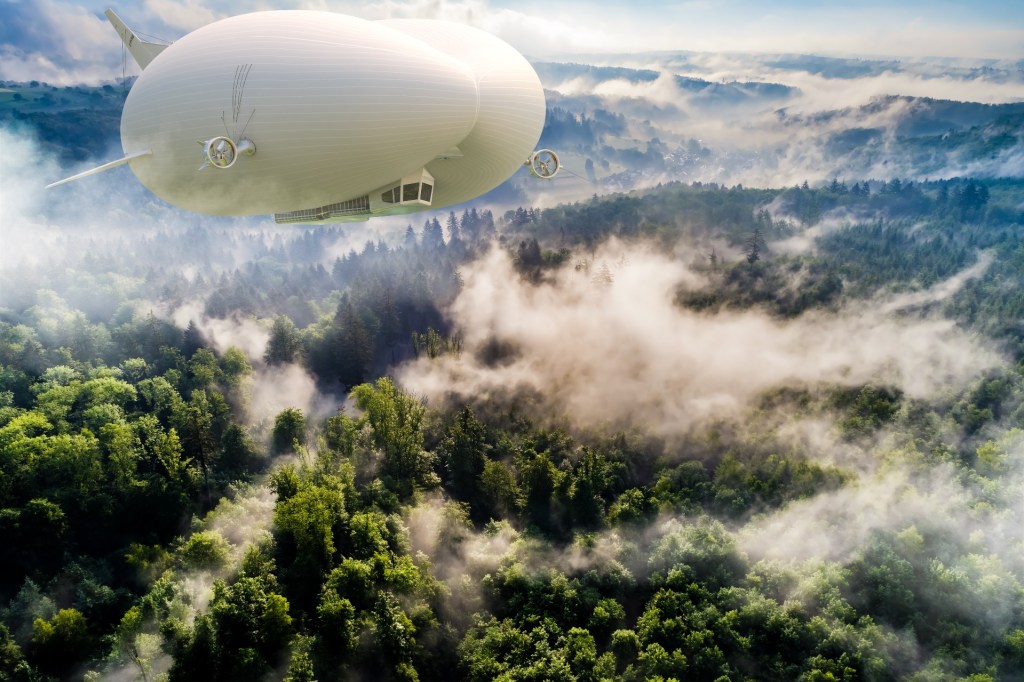 An Airlander 10 sails over a foggy forest