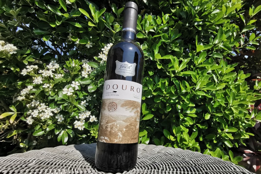 Tesco Finest Douro red pictured in the sun against a flowering backdrop