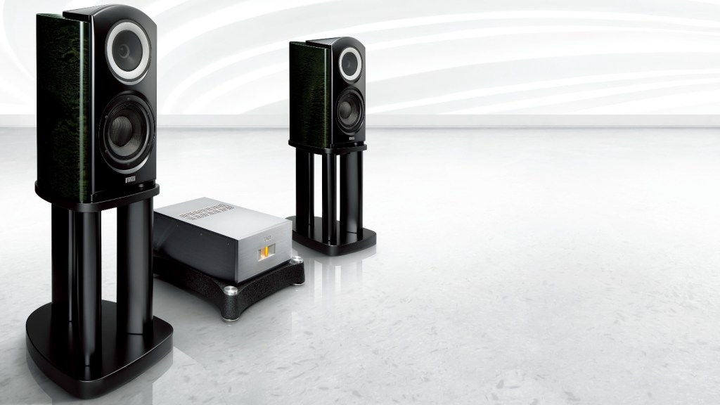 A pair of TAD Labs CR1TX speakers, with lush green finish, stand either side of a heavyweight stereo amp