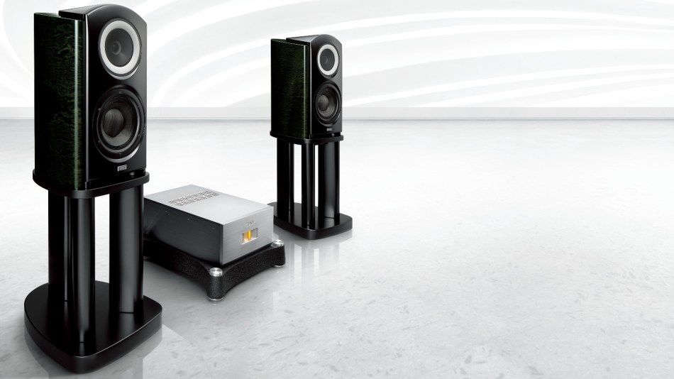 A pair of TAD Labs CR1TX speakers, with lush green finish, stand either side of a heavyweight stereo amp