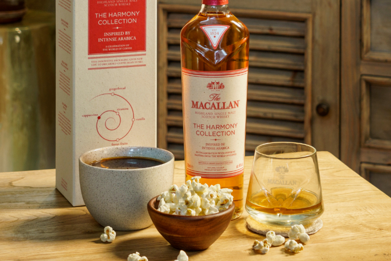 A bottle of Macallan Harmony Collection whisky alongside a cup of coffee and a bowl of popcorn