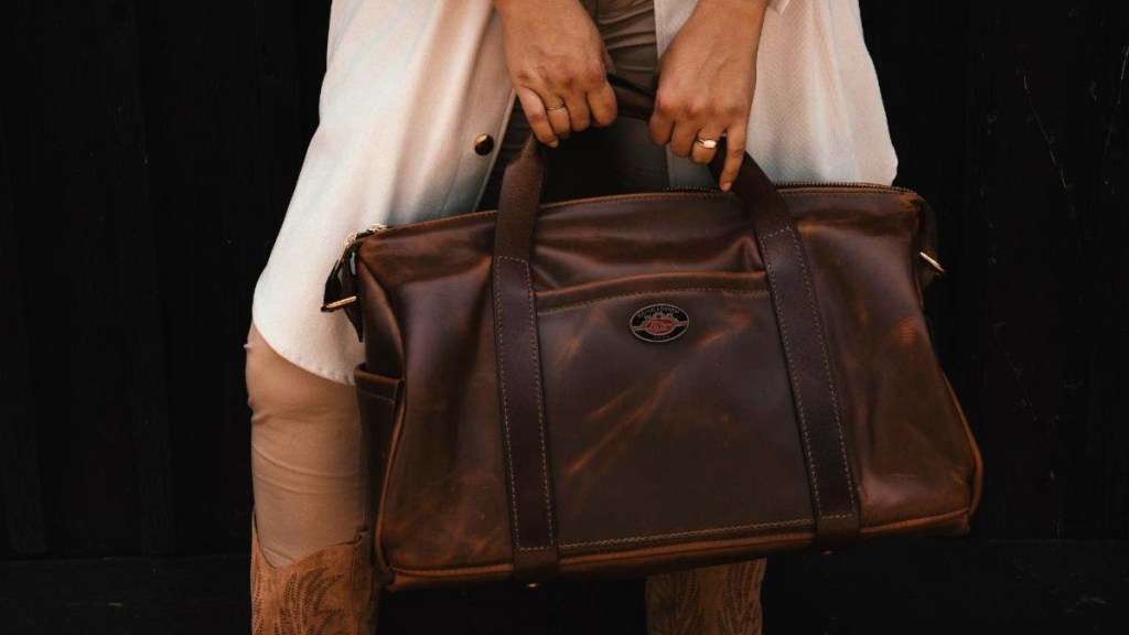 A lady in cowboy boots holds a Lifton Gibson duffle bag