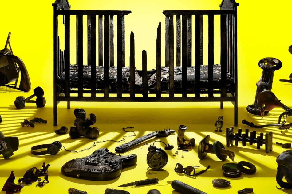 A child's cot surrounded by broken guitars and headphones