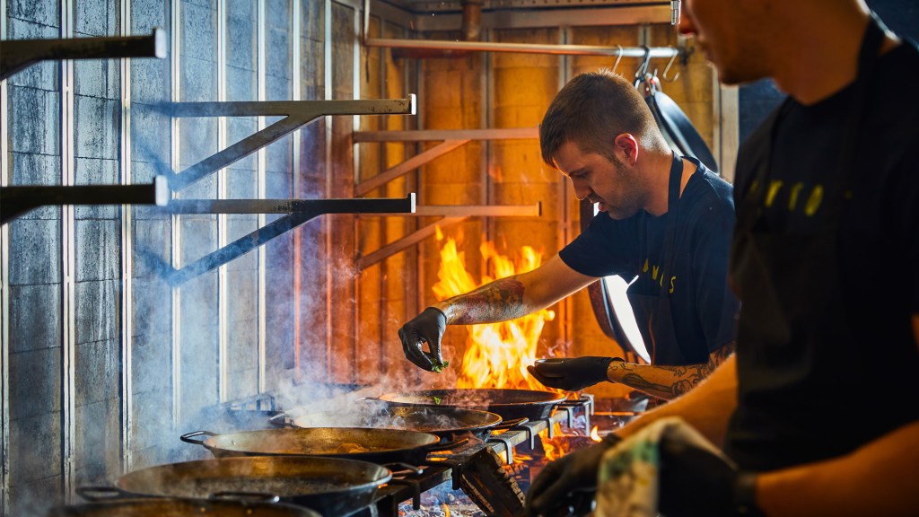 A chef hovers over the wood fires at Arros QD