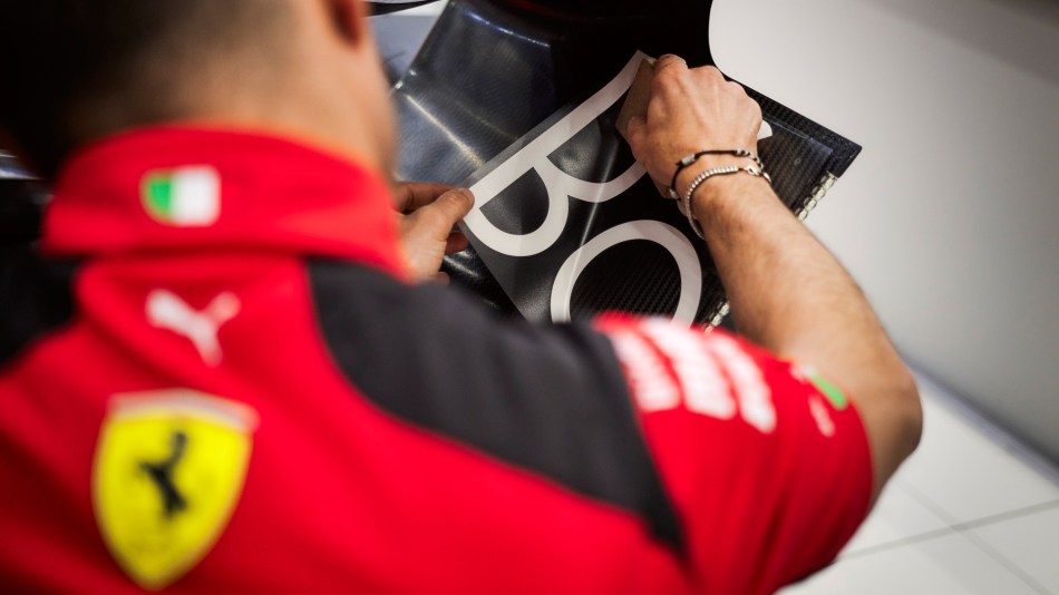 A Ferrari mechanic adds a Bang & Olufsen logo to an F1 car
