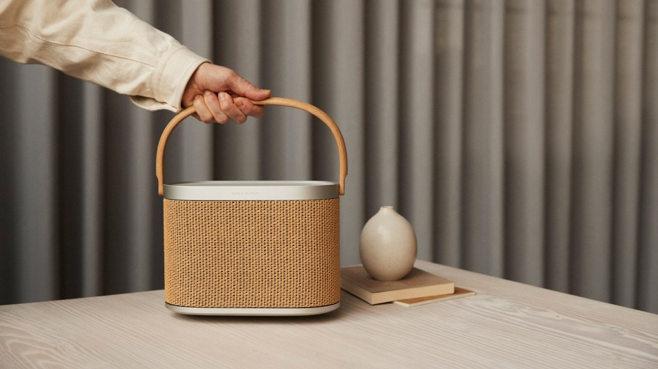 A hand grabs the handle of a Bang & Olufsen Beosound A5 portable speaker