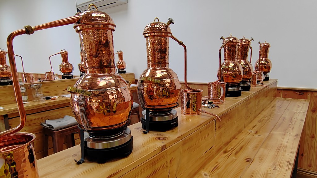 Copper stills on a long work bench at Ramsbury Estate Gin School