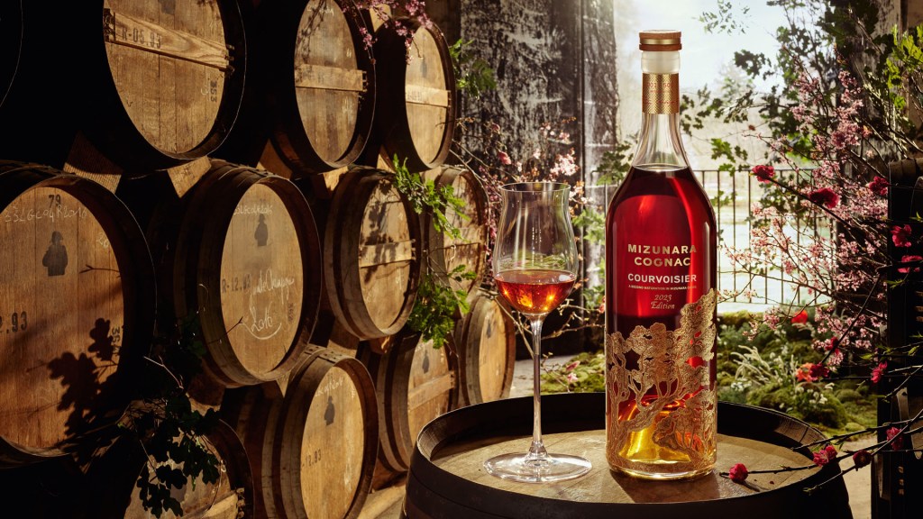 A bottle of Courvoisier Mizunara cognac against a background of barrels