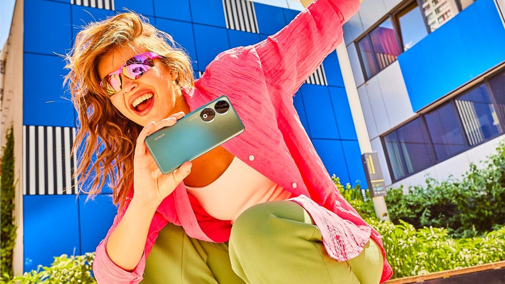 An Honor 90 smartphone being enthusiastically wielded by a young user