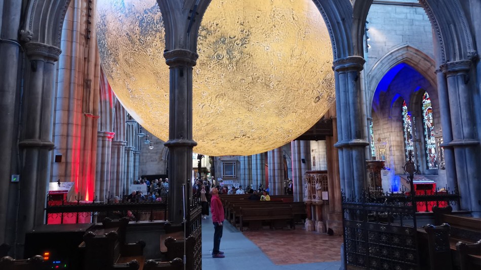 Man in red shirt looks up at Luke Jerram's Mars artwork inside St John the Baptist church London