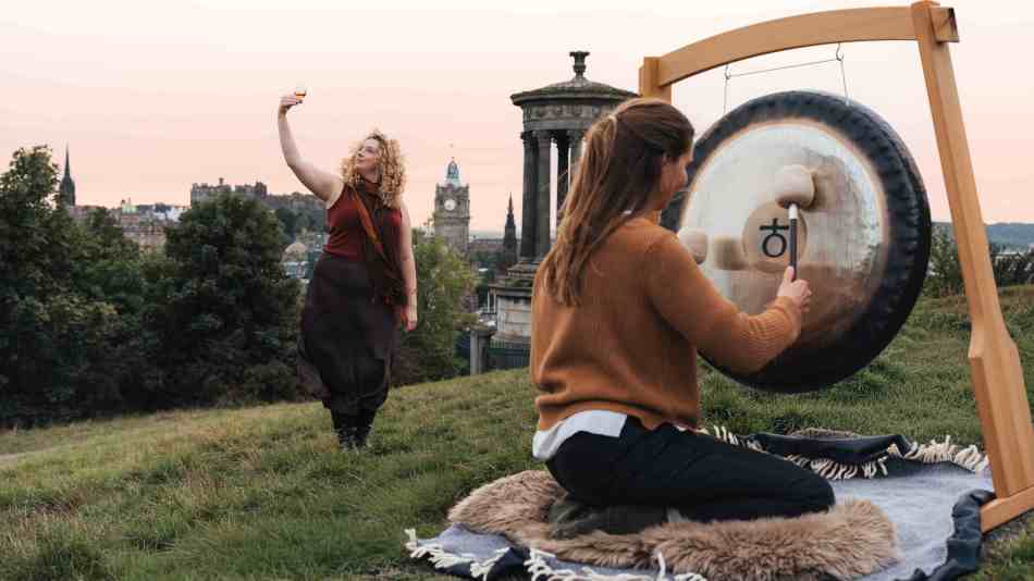 Madeleine Schmoll of The Scotch Malt Whisky Society rasing a toast to the start of whisky season on Calton Hill, Edinburgh, with Jo McCoy of Blissness, a gong sound bath practitioner