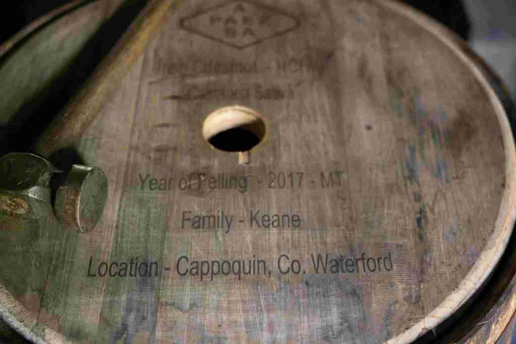 A close-up of a wooden barrel head engraved with 'Year of Telling - 2017 - MT', 'Family - Keane', and 'Location - Cappoquin, Co. Waterford'.